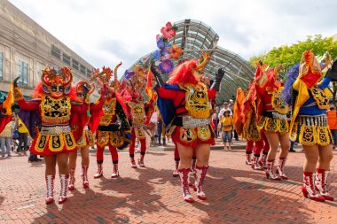 A group of dancers in colorful costumes perform in a city street
