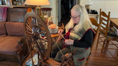 Woman spinning wool on a traditional spinning wheel, a Virginia Folklife craft.