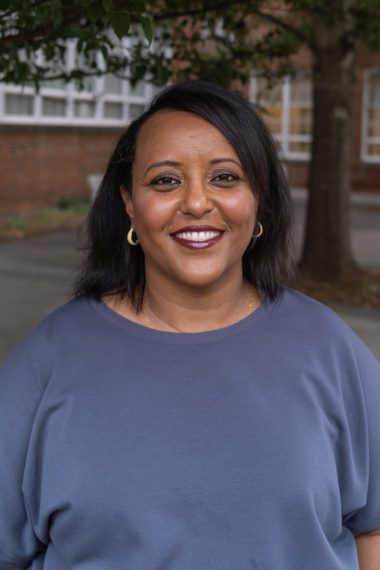 Portrait of a woman with dark hair and hoop earrings, smiling