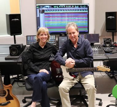 Man and woman in recording studio with guitars and mixing board