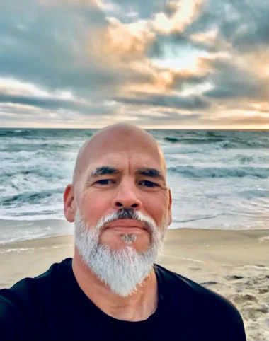 Matthew Quick at the beach with dramatic clouds and ocean waves